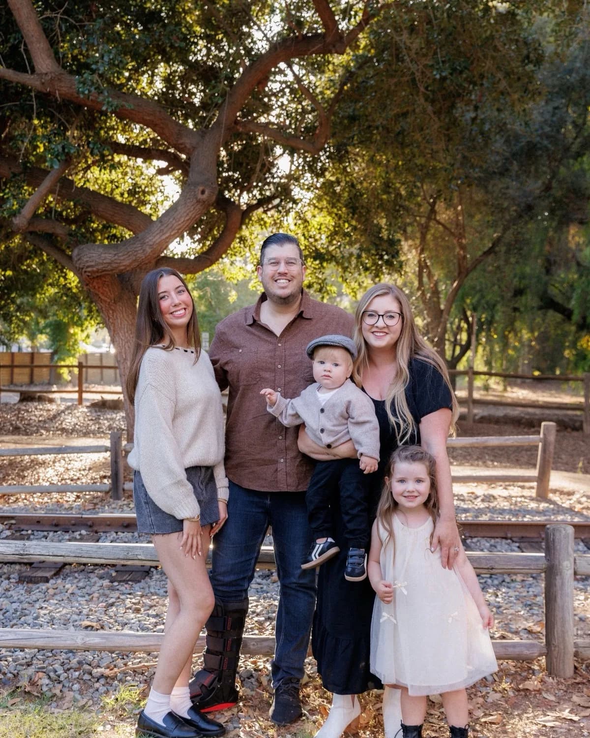 Greg with his wife and three kids, standing under an oak tree in the late afternoon